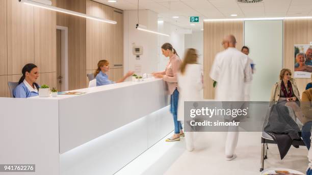 blurred motion of doctors walking in clinic, patients sitting on chair.